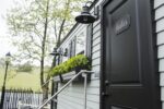 Black Tie Luxury restroom trailers exterior with vinyl siding, light fixtures, flower boxes, windows and dark trim