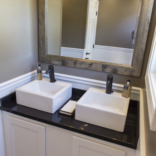 Black Tie Luxury restroom trailers interior with upgraded sinks, a mirror, trim, wood floors and light fixtures